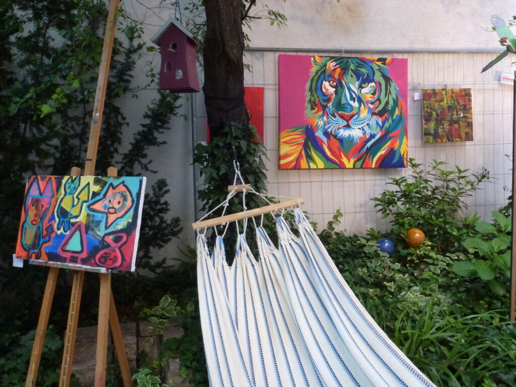 Der Garten in der Teschnergasse mit Hängematte und Kunstwerken.