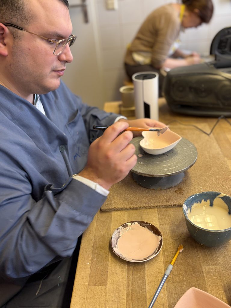 Ein Klient der Keramikwerkstatt beim bemalen einer herzförmigen Tonschale.