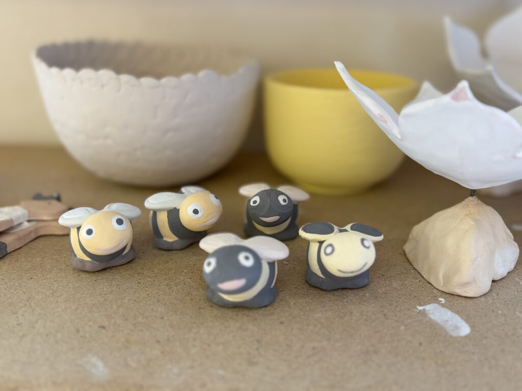 Fünf fertig bemalte Tonbienen.