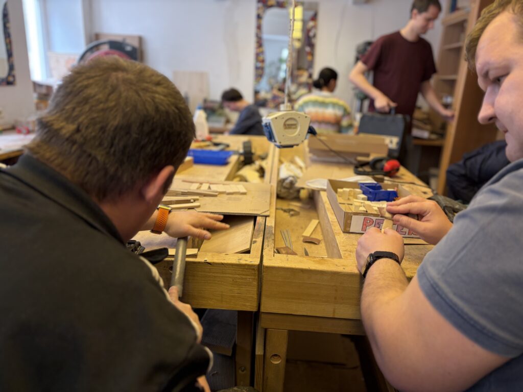 Zwei Klienten der Holzwerkstatt beim schleifen von Holz.