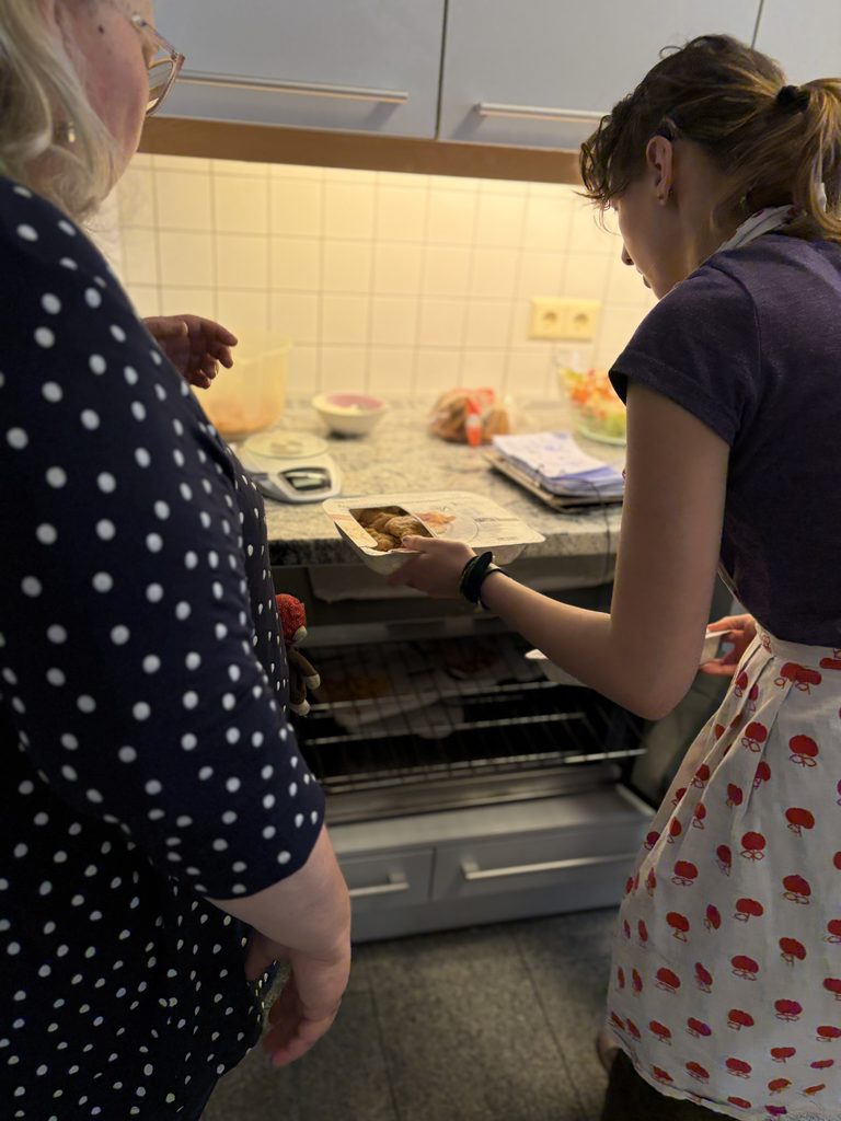 Eine Klientin der Haushaltsgruppe stellt essen in den Ofen.