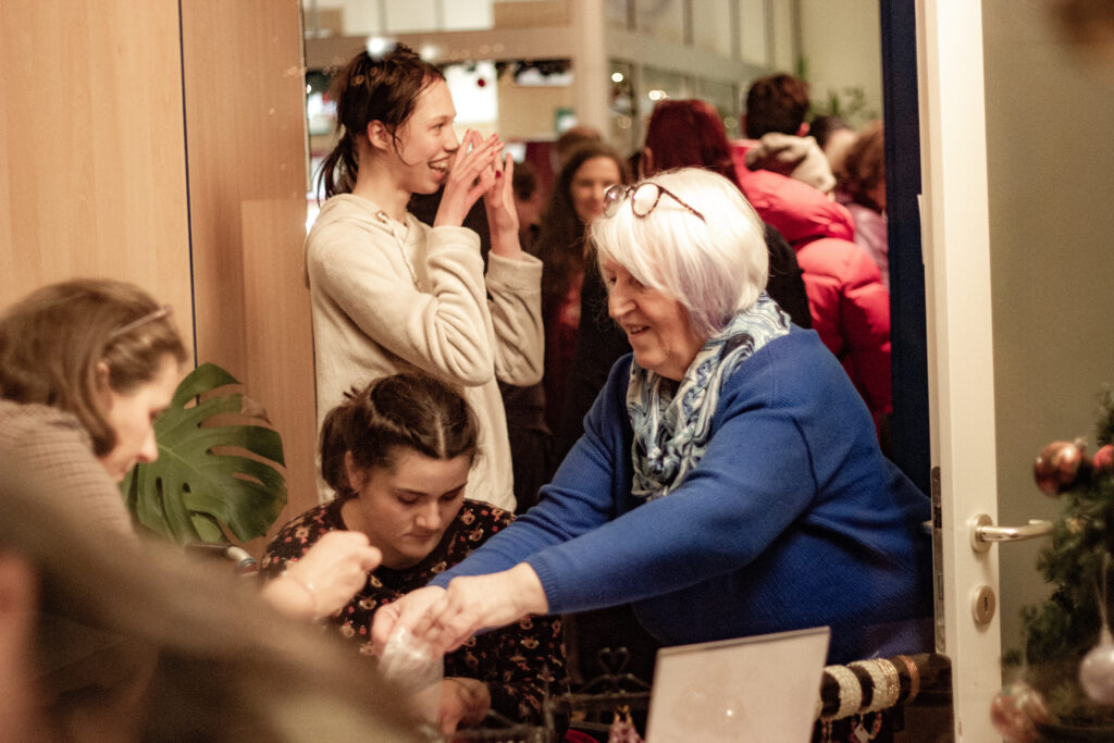 Mitarbeiterin packt mit einer Kundin Geschenke am Weihnachtsbasar ein.